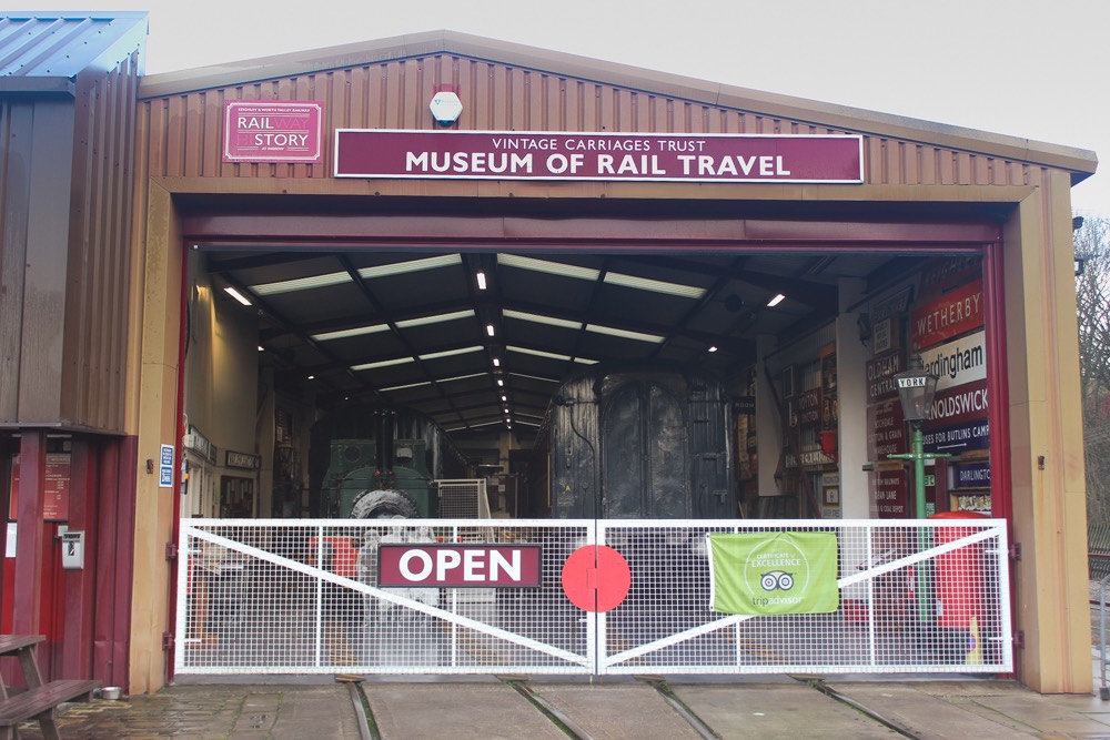 Exterior of Museum of Rail Travel, Keighley. Visible are a locomotive, numerous signs, and a lamp post