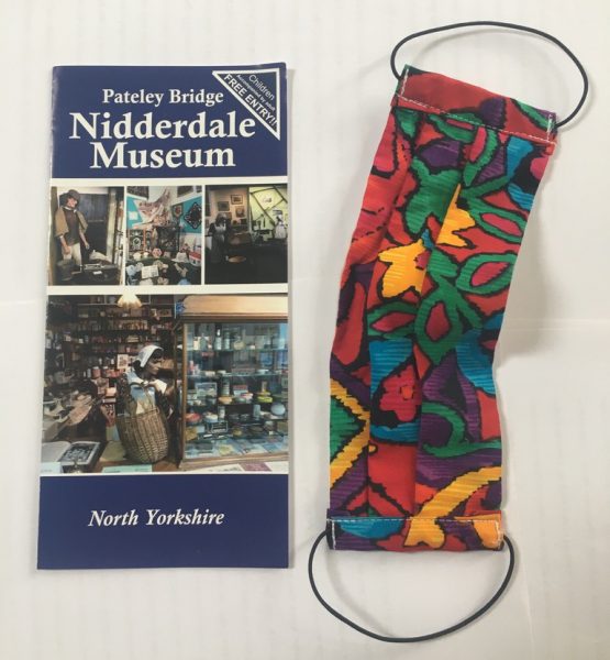 A colourful fabric facemask and a leaflet for Nidderdale Museum