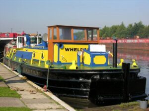 A tug painted in bright blue and yellow moored at the dockside.
