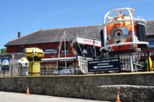 The exterior of Charlestown Shipwreck & Heritage Centre. Several buoys and a lifeboat stand on the forecourt, together with a submersible on a raised platform